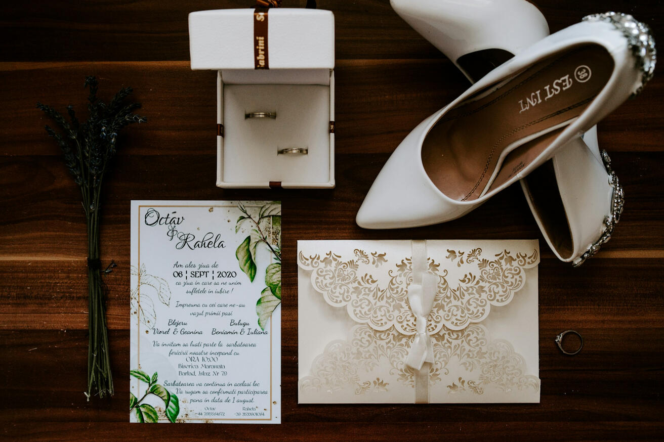 Photo by Acalinei Andi on Unsplash White invitation, envelope, ring box, and heels on a brown wooden table